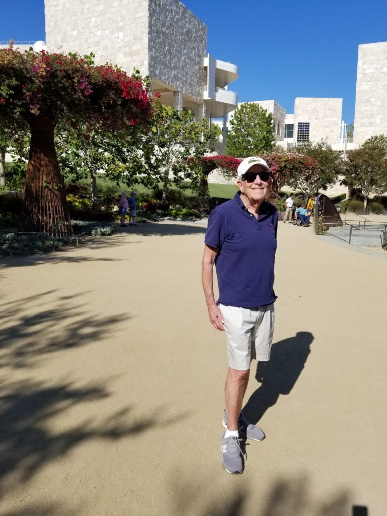 Man in a ballcap in front of white buildings